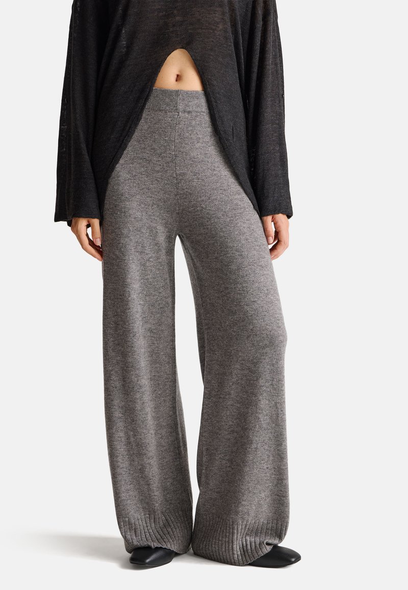 Graue weit geschnittene Hosen aus weichem, gestricktem Stoff. Sie verfügen über einen gerippten Bund und eine strukturierte Detailverarbeitung am Saum, die eine lockere Passform bietet.