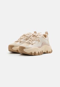 Sneaker beige con tomaia testurizzata, caratterizzate da accenti marrone chiaro, suole decorate e un design chunky. Lacci e linguetta per una facile calzata.