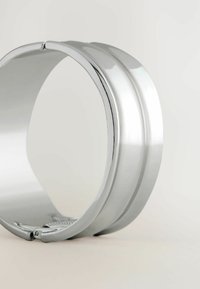 Metallinen rannekoru, jossa on kiillotettu hopeapinta. Ominaisuudet: pyöreä muoto, sileä tekstuuri ja segmentoitunut nauha, jossa on hienovaraisia uurteita.