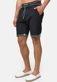 Sort shorts med et struktureret mønster, der har en justerbar talje, sidelommer og oprevne manchetter med kontrastfyldt grå kant.