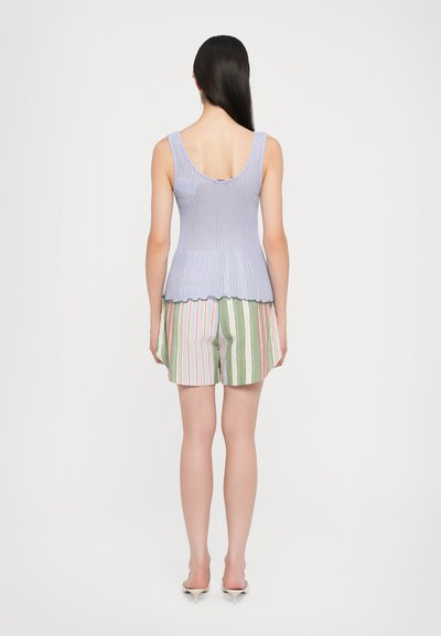 Débardeur lilas côtelé avec un dos en scoop, associé à un short rayé multicolore en vert, blanc et rouge. Texture lisse, silhouette ajustée.