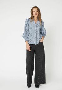 Blue and white striped blouse with puffed sleeves, paired with high-waisted wide-leg black jeans featuring eyelet details.