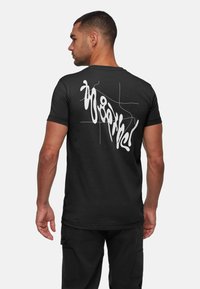 Svart bomullströja med en rundad vit grafisk design på baksidan. Fitted modell och korta ärmar. Förstärkt sömnad vid fållen.