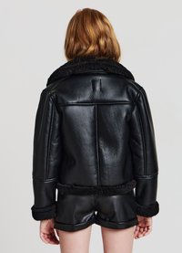 Schwarze Kunstlederjacke mit einem plüschigen, schwarzen Schafslederkragen und -besatz. Verfügt über ein kurzes Design und sichtbare Nähte.