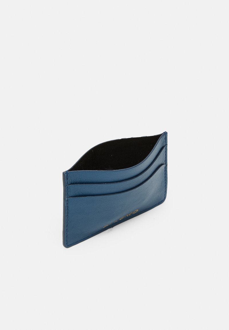 Læderkortholder i blå. Har fire kortlommer, glat tekstur og en afrundet topkant. Indvendigt er den foret med sort stof.