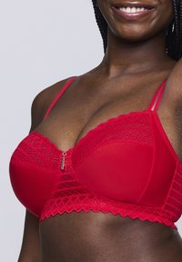 Rode kant beha met mesh cups, gedetailleerde kantafwerking en verstelbare bandjes. Een klein metalen accent is zichtbaar in het midden van de voorkant.