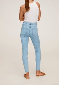 Jeans ajustados de color azul claro con una cintura alta, que cuentan con un diseño clásico de cinco bolsillos y un acabado de denin suave y texturizado.