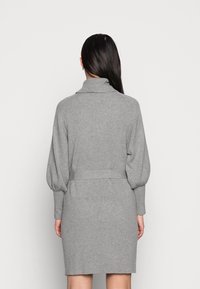 Graues Strickkleid mit hohem Kragen, Ballonärmeln und tailliertem Bund. Rippstruktur im gesamten Stoff, knielang.