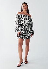 Schulterfreies Kleid mit einem schwarz-weißen Zebra-Streifenmuster, elastischem Bund und luftigen Ärmeln, aus leichtem Stoff gefertigt.