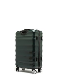 Valigia rigida verde scuro con una superficie strutturata e scanalata. Dotata di una maniglia nera e quattro ruote argento per la mobilità.