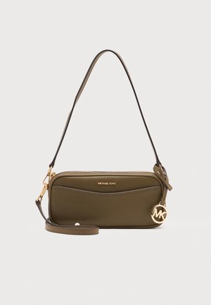 Маслиненозелена дамска чанта Michael Kors с преден джоб, дълга презрамка, елементи в златист тон и кръгъл висулка MK на светъл фон.
