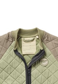 Veste matelassée avec des panneaux vert olive et kaki, une fermeture éclair sur le devant, un col côtelé et un logo de crocodile brodé sur la poitrine gauche.