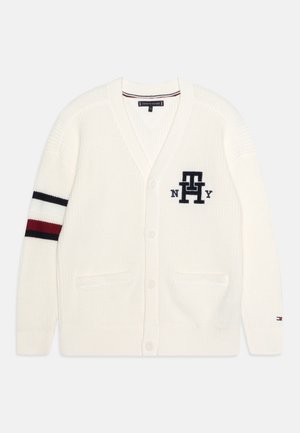 Biały dziergany sweter rozpinany z przodu na guziki, czarno-czerwone paski na lewym rękawie oraz logo „TH NY” na piersi.