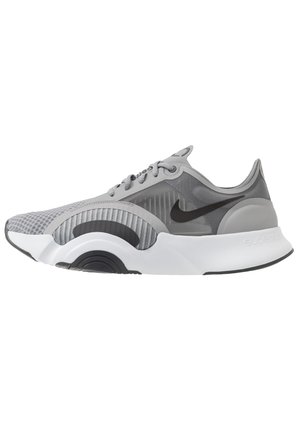 Chaussure de sport Nike grise et noire avec dessus en mesh, semelle blanche et noire incurvée et logo Nike noir sur le côté, vue de gauche.