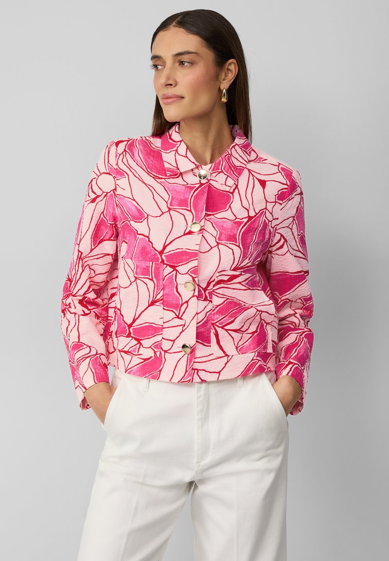 Veste à motif floral rose avec un design court, un col mandarin et une fermeture à boutons à l'avant. Assortie à un pantalon blanc à taille haute.
