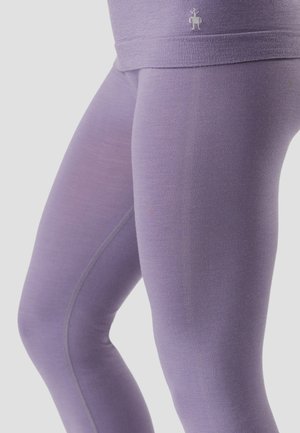 Primo piano di gambe che indossano leggings da allenamento senza cuciture color lavanda con un piccolo logo a forma di robot vicino alla vita.