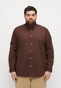 Brun knapper skjorte med en tilpasset krage, lange ermer og en glatt tekstur, med hvite knapper nedover fronten.