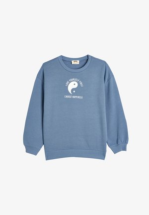 Blauwe sweater met een ronde hals, lange mouwen, geribbelde manchet en een wit grafisch ontwerp met tekst en een yin-yang symbool.