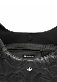 Wnętrze czarnej pikowanej torby z gładką podszewką, kieszenią na zamek i wytłoczonym logo. Zawiera zatrzask i elegancki design.