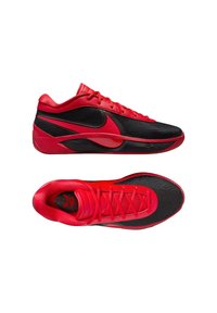 Scarpe da ginnastica rosse e nere con una tomaia in rete e sintetico, accentuate da un audace swoosh Nike, caratterizzate da una superficie testurizzata e un sistema di allacciatura.