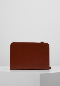 Braune Lederhandtasche mit rechteckiger Form, glatter Textur und abgerundeten Ecken. Verfügt über einen Reißverschluss und dezente goldene Hardware-Akzente.