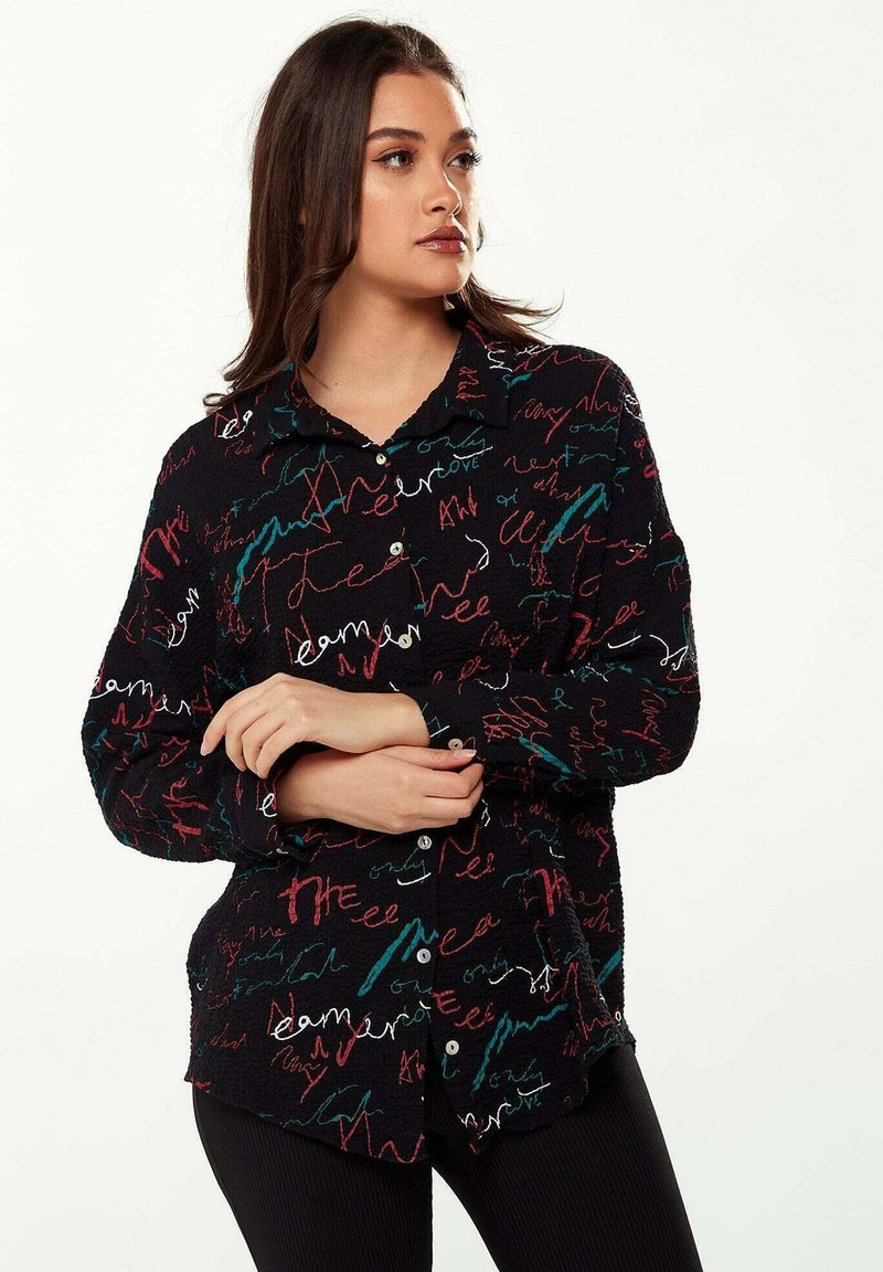 Black button-up shirt featuring a textured fabric with colorful, abstract handwriting patterns in red, teal, and white.