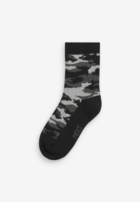 Schwarze Socke mit grauem Camouflage-Muster, aus weichem Material, mit geripptem Bund und verstärkter Zehenpartie. Markenname "NEXT" sichtbar.