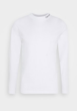 Chemise blanche à manches longues avec un col rond, avec un petit logo « Calvin Klein » imprimé près du col sur le côté droit.