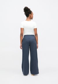 Wide-leg navy trousers with a soft, textured fabric and an elastic waistband, paired with a fitted white short-sleeve top.