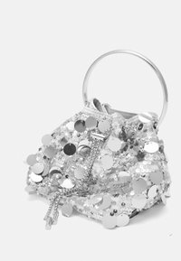 Bolso de mano plateado con lentejuelas, con un asa metálica circular, que presenta un diseño arrugado, tejido texturizado y cierre decorativo de cordón.