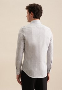 Camicia a maniche lunghe grigia chiaro con un piccolo motivo floreale, polsini con bottone e colletto classico. Tessuto liscio con una leggera lucentezza.