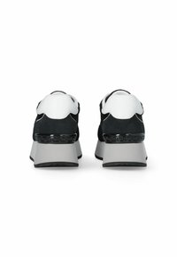 Zapatillas deportivas de ante negro y cuero blanco con un tacón grueso gris y herrajes decorativos en negro. Diseño redondeado con acentos texturizados.