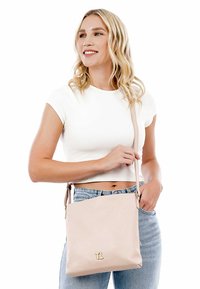 Borsa a spalla in pelle rosa chiaro con una superficie liscia, dotata di accessori in oro e del logo "TL". Tracolla regolabile per opzioni di trasporto versatili.