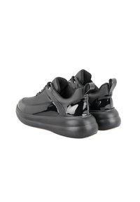 Schwarze Sneaker mit einem glatten Obermaterial aus Lackleder, gepolstertem Kragen und einer dicken Gummisohle. Schnürdesign mit einer Zuglasche hinten.