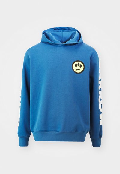 Blue hoodie made of cotton blend, features a round yellow logo with black outlined angry face, white text on the sleeve, and a kangaroo pocket.