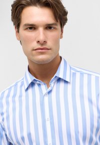 Lichtblauw en wit gestreept shirt van soepel materiaal, met een button-down kraag en een klassieke pasvorm. De knopen aan de voorkant zijn zichtbaar.