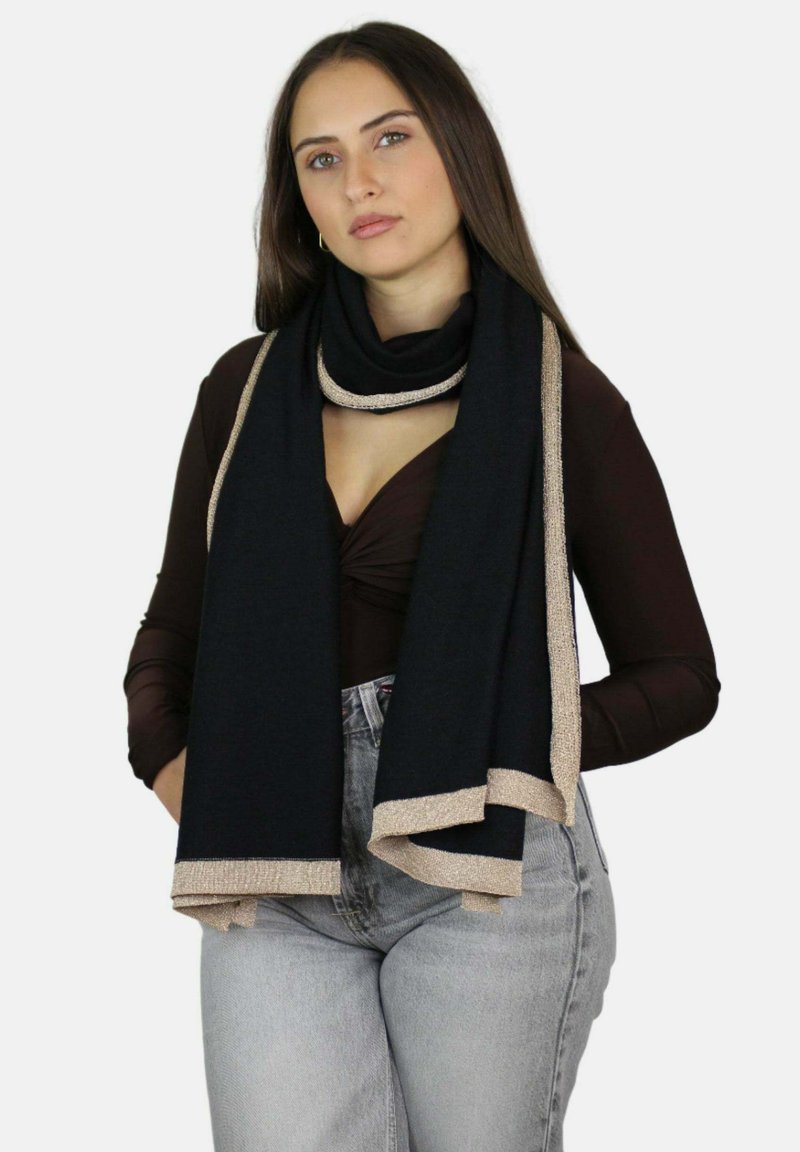 Écharpe noire avec bordure métallique dorée. Tissu doux et texturé qui se drape élégamment autour du cou. Tenue décontractée avec un décolleté plongeant et un jean taille haute.