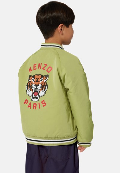 Groene bomberjack met zwart-wit gestreepte manchetten. Heeft een groot tijgerontwerp en "KENZO PARIS"-tekst op de achterkant. Glad textuur.