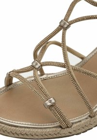 Sandalo espadrilla con cinturini, caratterizzato da una tomaia in oro metallico con cinturini testurizzati e una suola in juta intrecciata. Soletta imbottita in un delicato color beige.