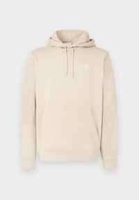 Bézs színű kapucnis pulóver puha anyagból, kenguru zsebbel, húzózsinóros kapucnival és fehér Adidas logóval a mellrészen. Hosszú ujjú, bordázott szegélyekkel.