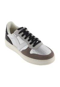 Sneaker a bassa punta con pannelli bianchi, grigi e argentati, lacci neri, suola texturizzata e colletto imbottito di colore crema, mostrato da un angolo leggermente inclinato.