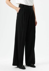Schwarze Hosen mit weitem Bein und Falten, hohem Bund, seitlichen Taschen und Knopfverschluss. Verfügt über eine glatte Textur und einen maßgeschneiderten Schnitt.