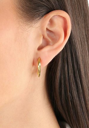 Pendientes de aro de oro con un diseño trenzado, de grosor medio y textura suave, que complementan la oreja sin sujetadores visibles.