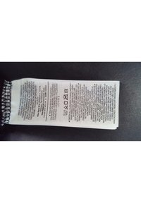 Bílá štítek péče o textil s černým textem, který obsahuje pokyny k praní a složení materiálu. Obsahuje symboly péče a překlady do několika jazyků.
