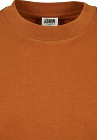 Tricou din bumbac organic, cu guler rotund, în nuanța portocalie arsă, având un guler texturat, cu nervuri și detalii de cusătură subtile.