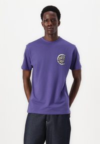 Purple cotton t-shirt with short sleeves, featuring a "Santa Cruz" logo graphic on the left chest. Round neck, casual fit.
