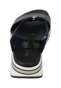 Marineblauwe sandaal met een suedestrook, een gestructureerde voering en een witte platformzool met zwarte en grijze strepen. Verfraaid met een metalen gesp.