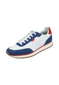 Zapatilla blanca con acentos de gamuza azul y un talón rojo. Presenta un cierre de cordones blanco, suela de goma texturizada y una pequeña etiqueta de logo roja.