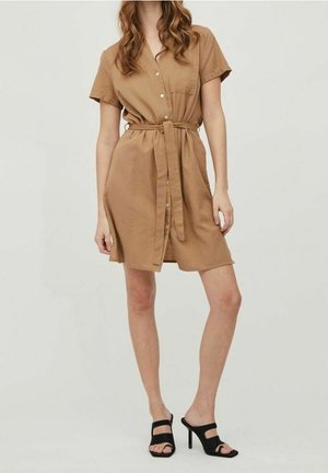 Robe courte à manches courtes avec devant boutonné, taille ceinturée, ourlet à hauteur du genou et coupe décontractée. Associée à des sandales à talons hauts noires.