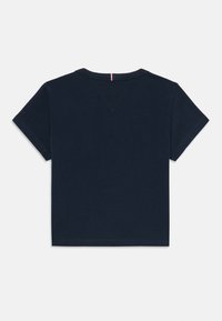 T-shirt en coton marine à manches courtes, col rond, avec une petite touche rouge au dos au niveau de l'encolure. Texture lisse, design simple, coupe régulière.